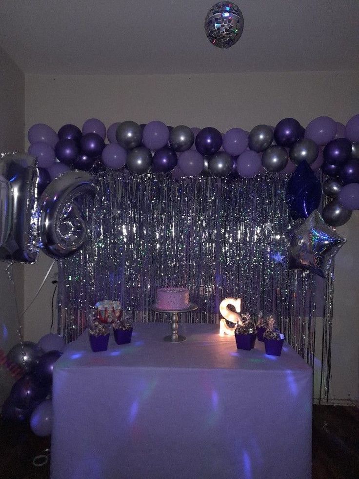 the table is set up with purple and silver balloons