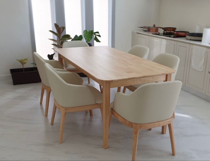 a dining room table with chairs and a potted plant on the counter top in front of it