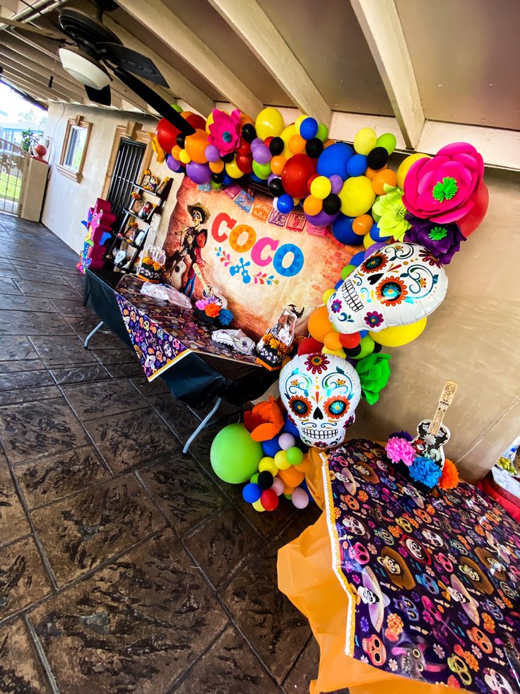 a table covered in balloons and decorations for a mexican day of the dead party