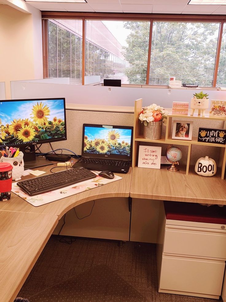 an office desk with two computer monitors and a laptop on it, in front of a window