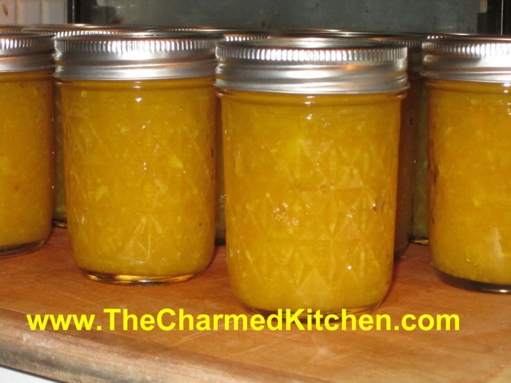 four jars filled with yellow liquid sitting on top of a wooden counter