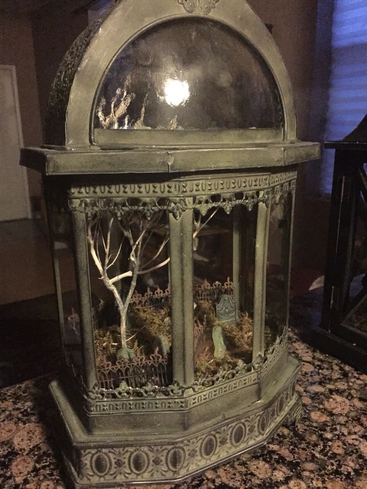 an old fashioned clock on top of a granite counter with trees and bushes in it