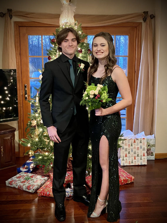 A young couple wearing formalwear posing in front of a Christmas tree Black Suits With Green Ties, Black Suit With Green Tie, Black Suit Green Tie, Green And Black Suit, Men's Black Suit, Formal Inspiration, Forest Green Dresses, Prom Suit, Black Suit Men