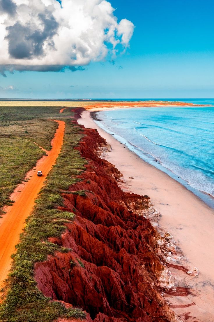 an aerial view of the red sand and blue water at low tide beach in australia