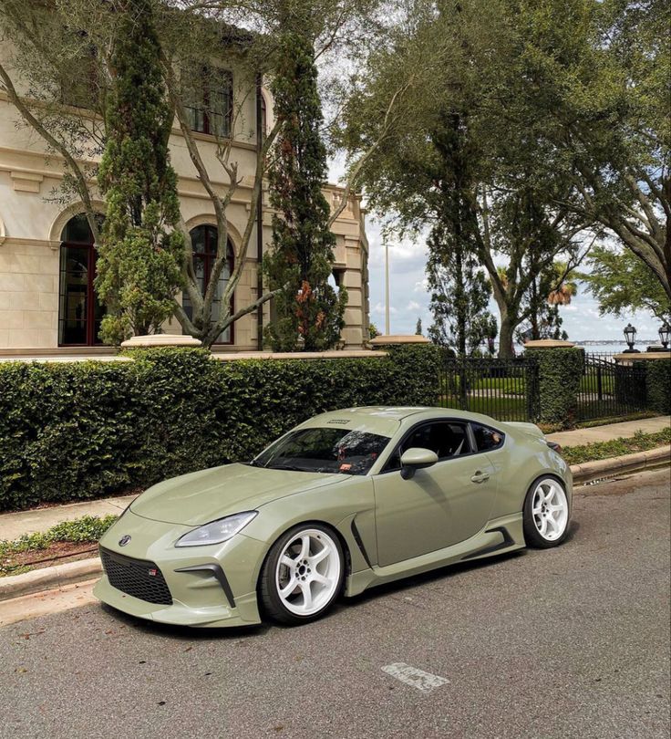 a green sports car parked in front of a house