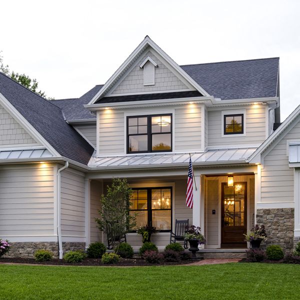 a large white house with an american flag on the front door and lights in the windows