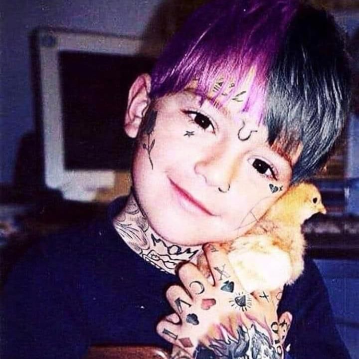 a boy with tattoos holding a chicken in his hands