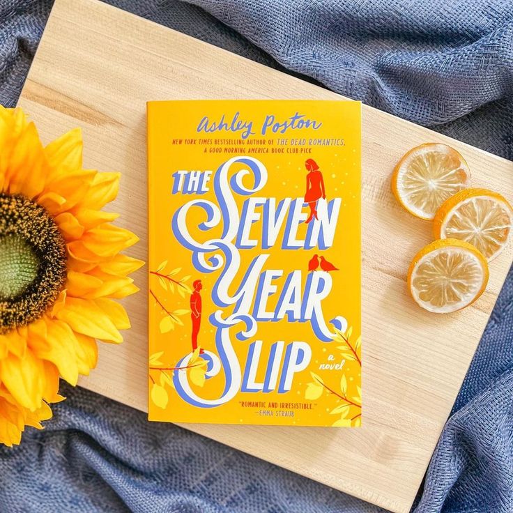 the seven year slip book next to sliced lemons and a sunflower on a blue blanket