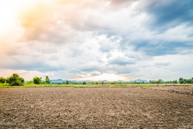 an empty plowed field under a cloudy sky