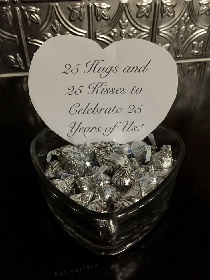 a glass bowl filled with silver foil and a sign that says 25 hugs and 29 kisses to celebrate 35 years of us