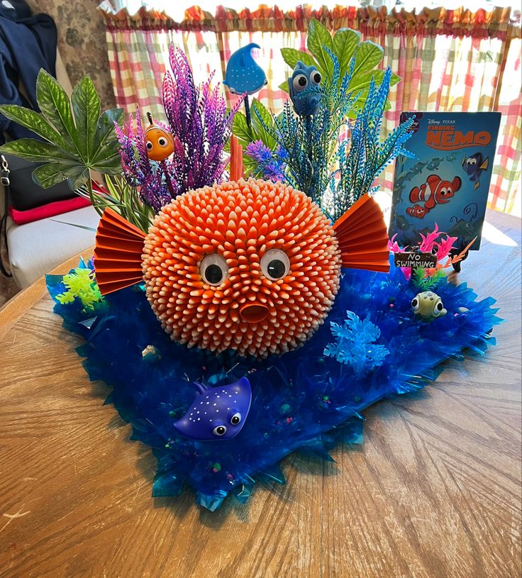 an orange and blue fish decoration sitting on top of a table next to a book