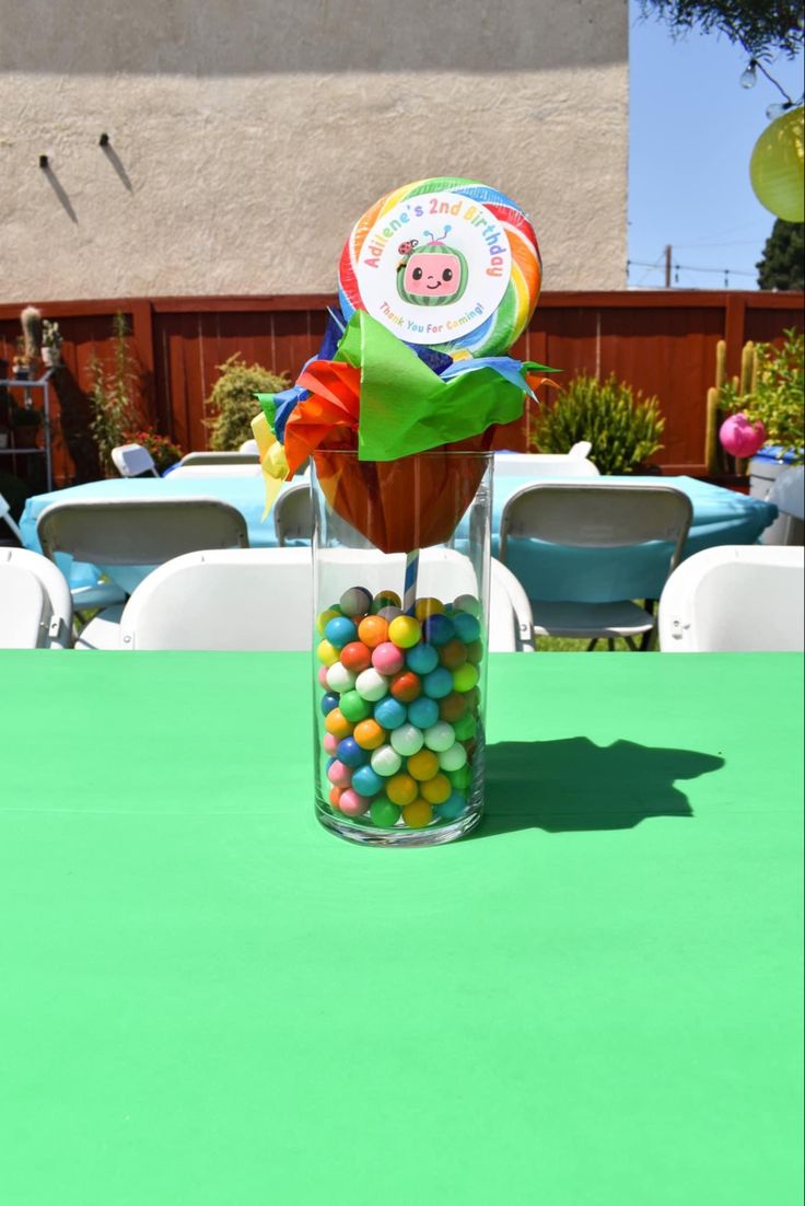 a vase filled with candy sitting on top of a green tablecloth covered patio area