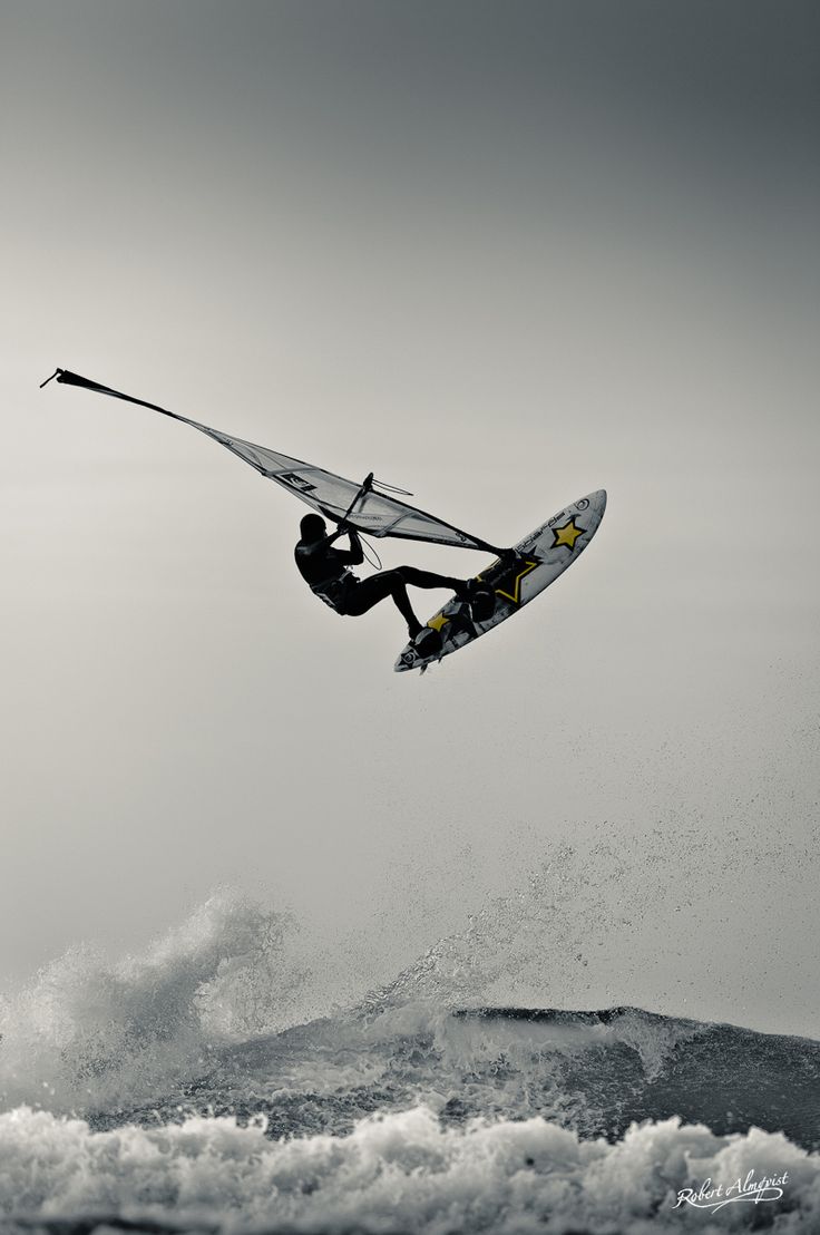 a person on a surfboard is in the air above water and waves while holding onto a rope