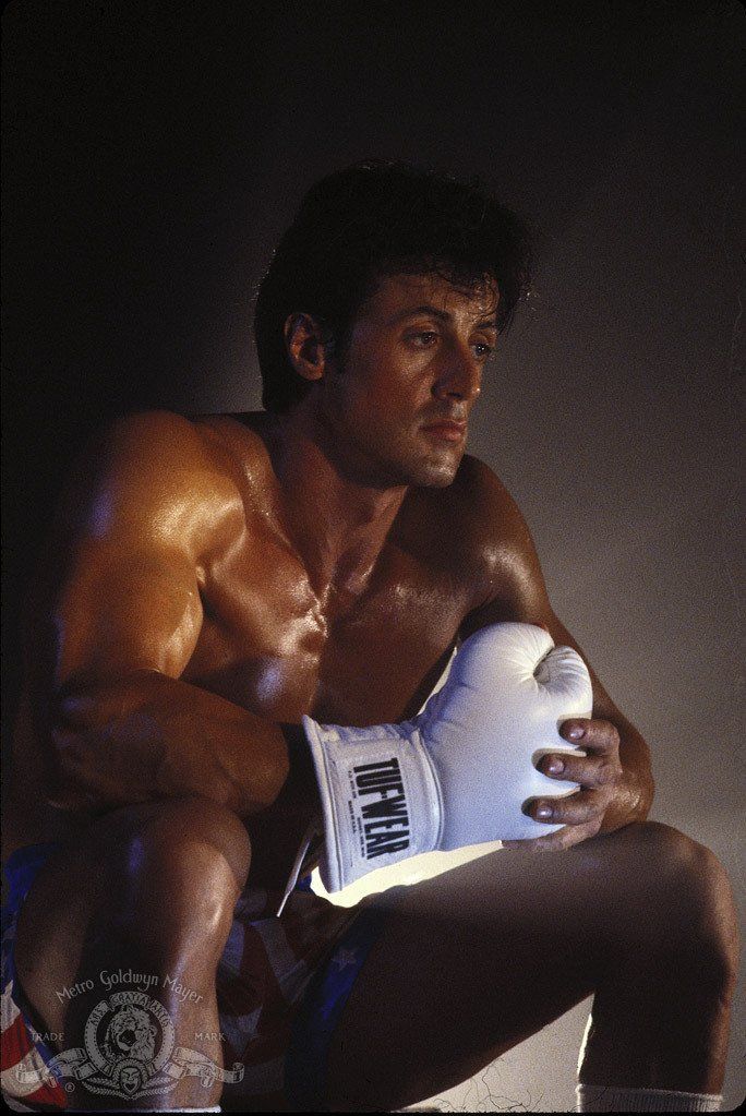 a shirtless man sitting down holding a white ball