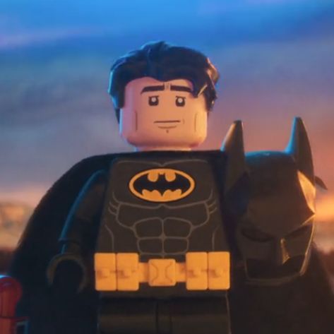 the lego batman movie character is standing in front of a blue sky with clouds behind him