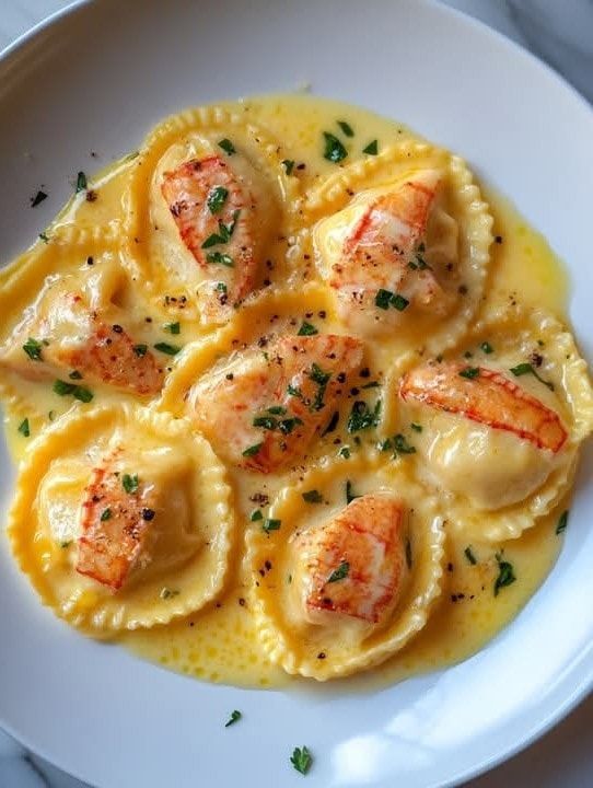 a white plate topped with ravioli and shrimp covered in sauce on top of a marble table