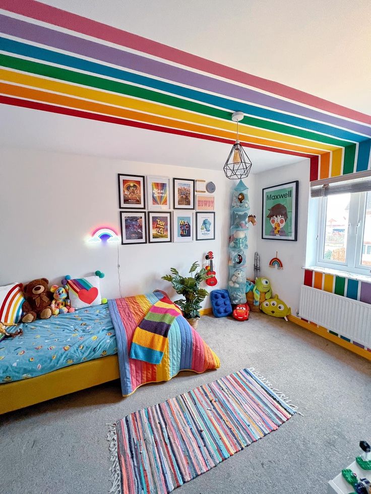 a bedroom with rainbow painted on the ceiling and pictures hanging above the bed in front of it