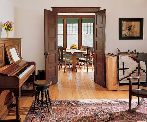 a living room filled with furniture and a grand piano in front of a doorway to another room