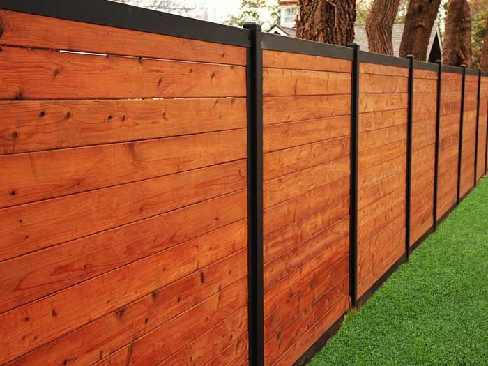 a wooden fence with black posts and grass