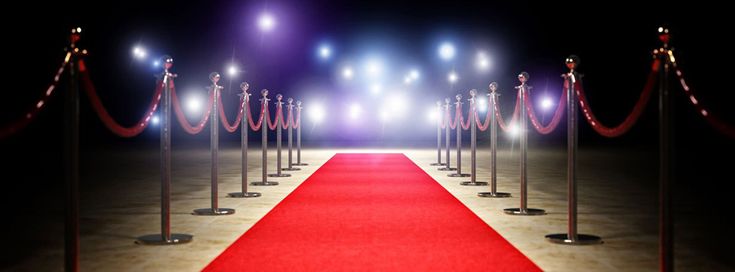 a red carpet is lined up with stance barriers and roped off poles on either side