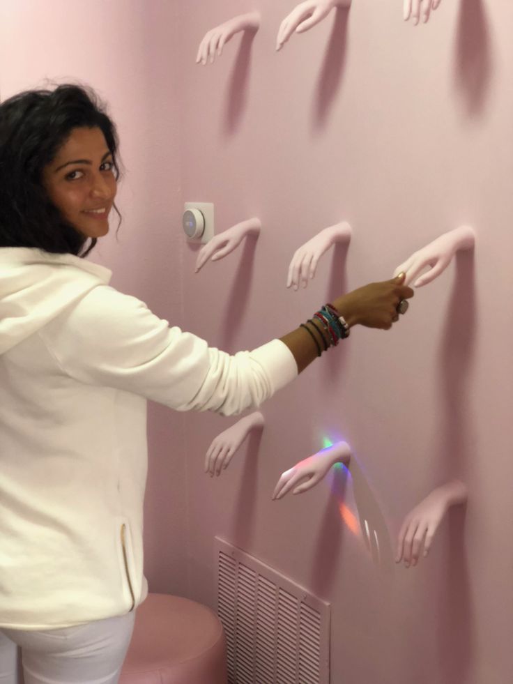 a woman is pointing to the wall with her hands on it and lights coming from them