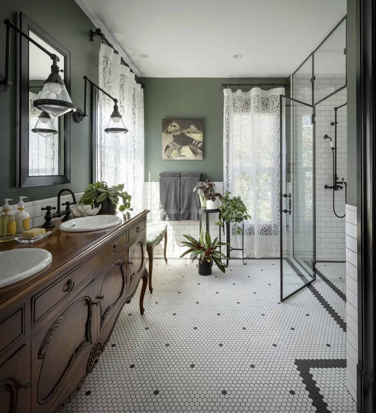 a large bathroom with green walls and white tile flooring, along with two sinks