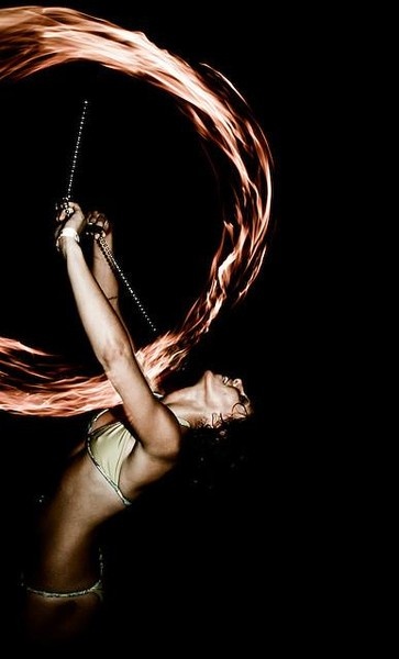 a woman with long hair is spinning a fire hula hoop on her head and hands