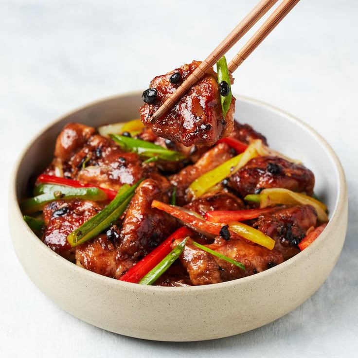 meat and vegetables in a bowl with chopsticks