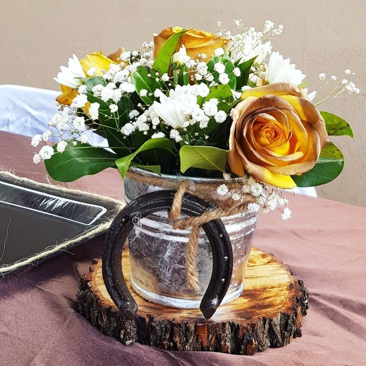 a bouquet of flowers in a glass jar on a wooden stand next to an empty tray