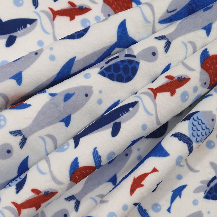 the fabric has fish on it and is white with blue, red and gray colors