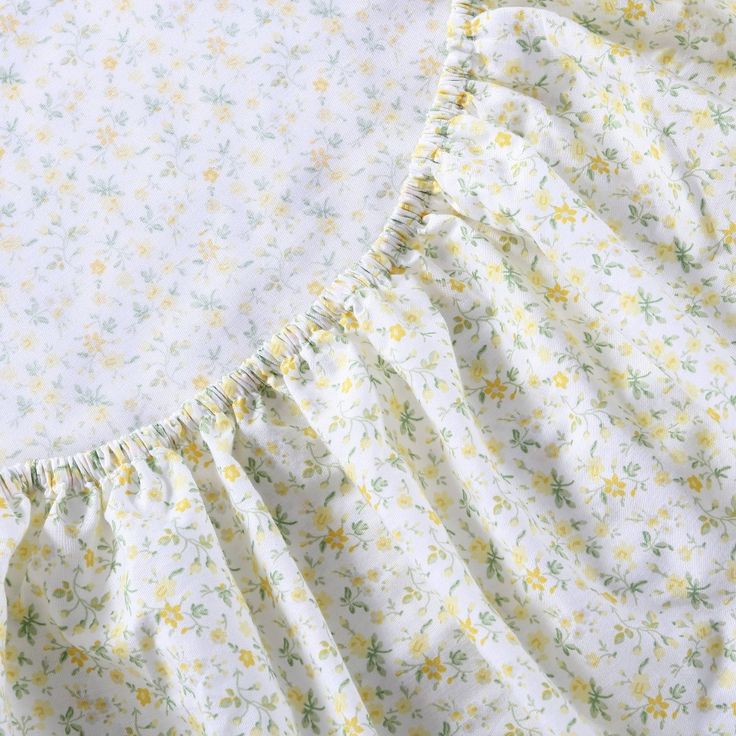 a white and yellow floral print dress with ruffles on the bottom, sitting on top of a bed