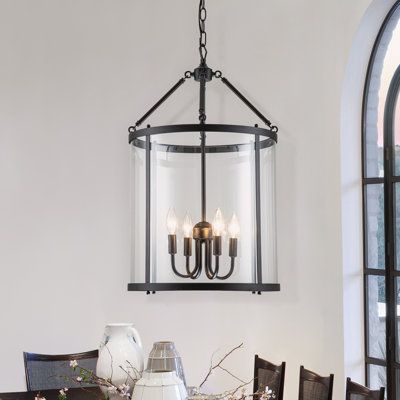 a chandelier hanging from the ceiling over a dining room table with flowers on it