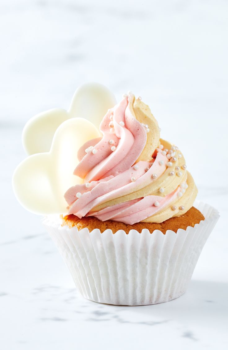 a cupcake with pink icing and white frosting on it's top