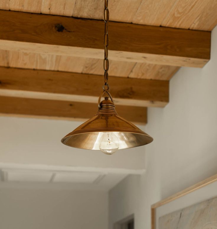 a light fixture hanging from the ceiling in a room with wood beams and exposed lighting