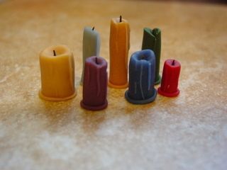 four different colored candles sitting on top of a table next to each other in rows