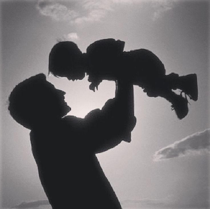 the silhouette of a man holding a baby in his arms