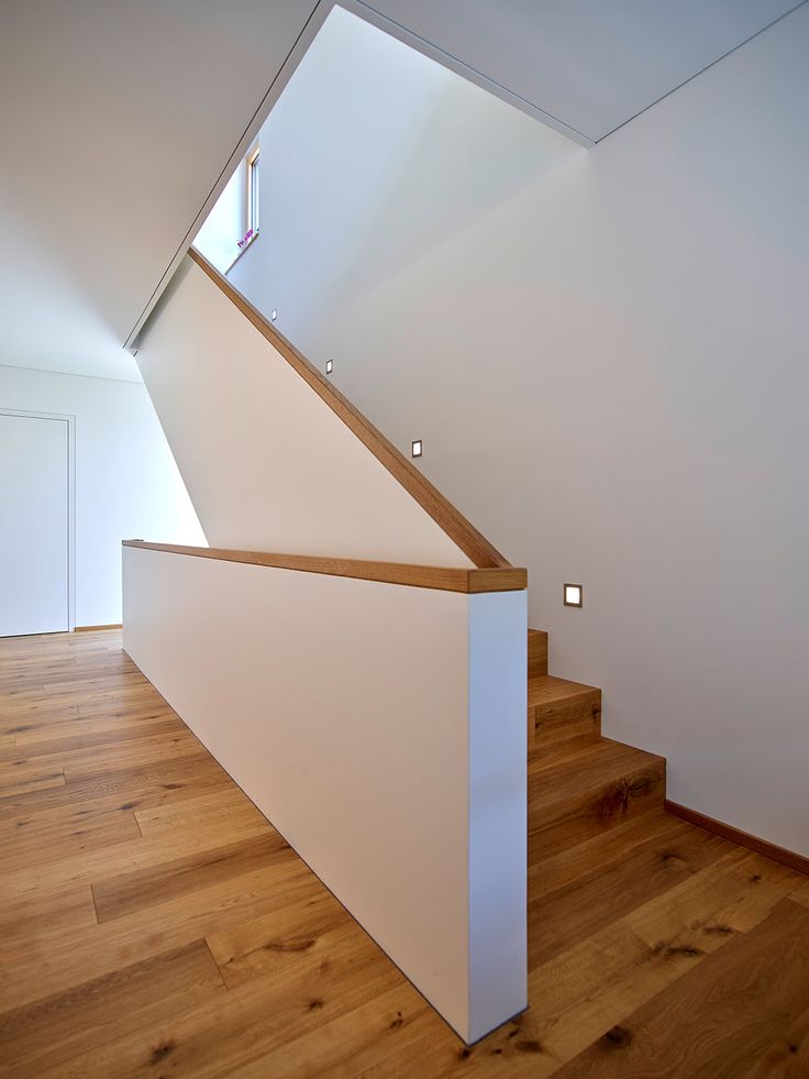 an empty room with wood flooring and white walls, along with a stair case