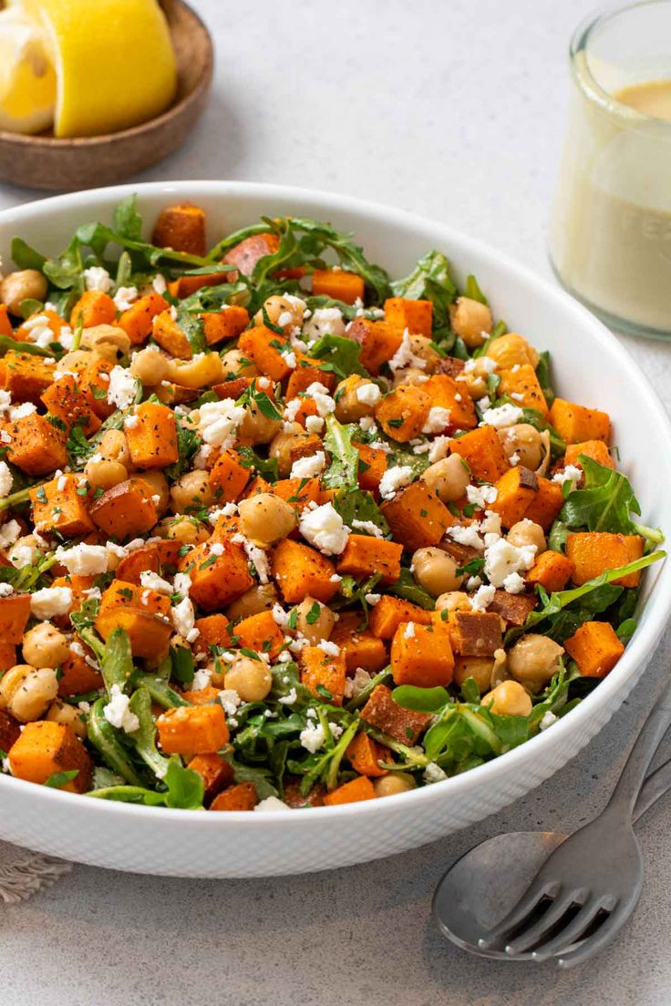 a salad with chickpeas, spinach and feta cheese in a white bowl