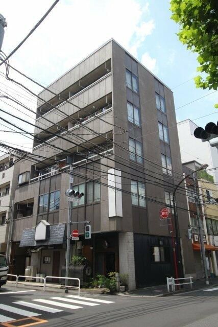 an apartment building on the corner of a street with traffic lights in front of it