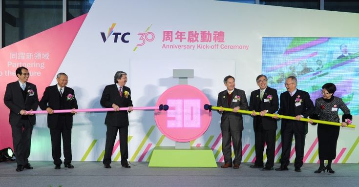 several men in suits are holding a pink ribbon at the end of a large ceremony