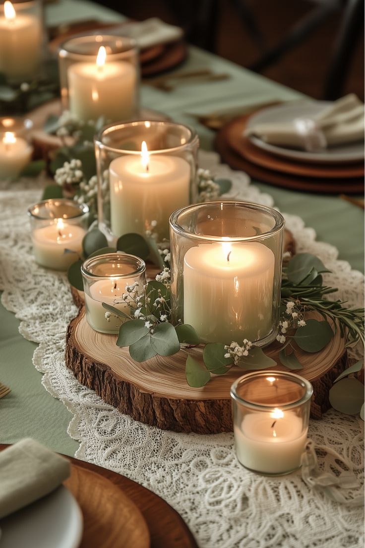 candles and greenery are arranged on a wood slice at the center of a table