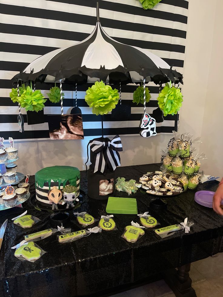 a table topped with cakes and cupcakes under an umbrella