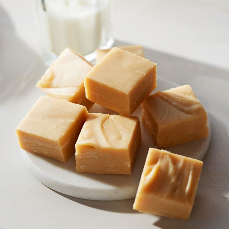 several pieces of butter on a plate with a glass of milk in the back ground