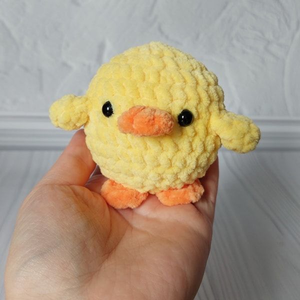 a small yellow stuffed animal in someone's hand