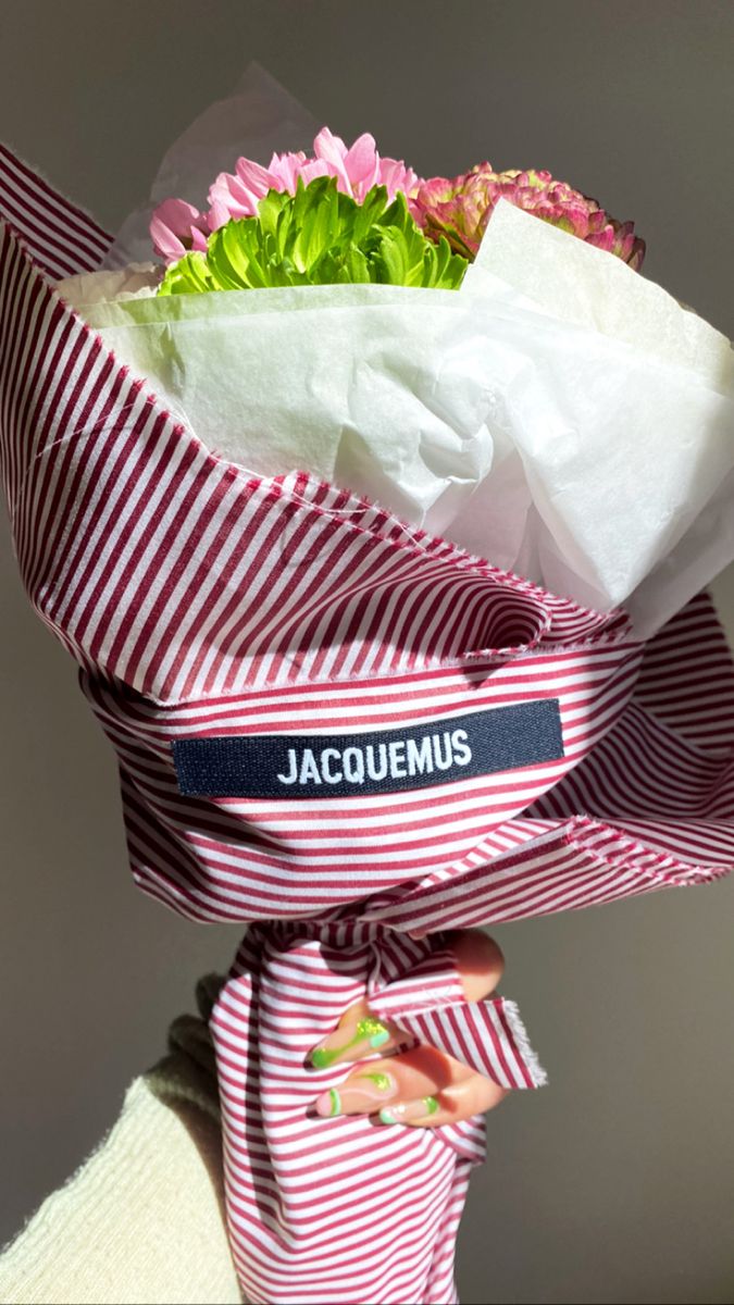 a bouquet of flowers wrapped in red and white striped paper with the name jacquamus on it