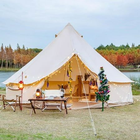 a white tent with lights and decorations on the outside is set up in front of a lake