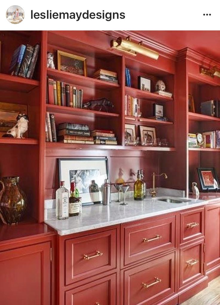 a kitchen with red cabinets and marble counter tops