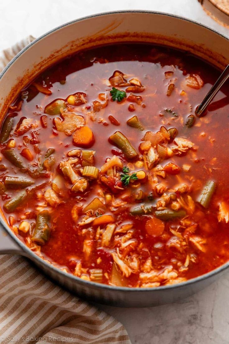 a pot full of vegetable soup with bread on the side