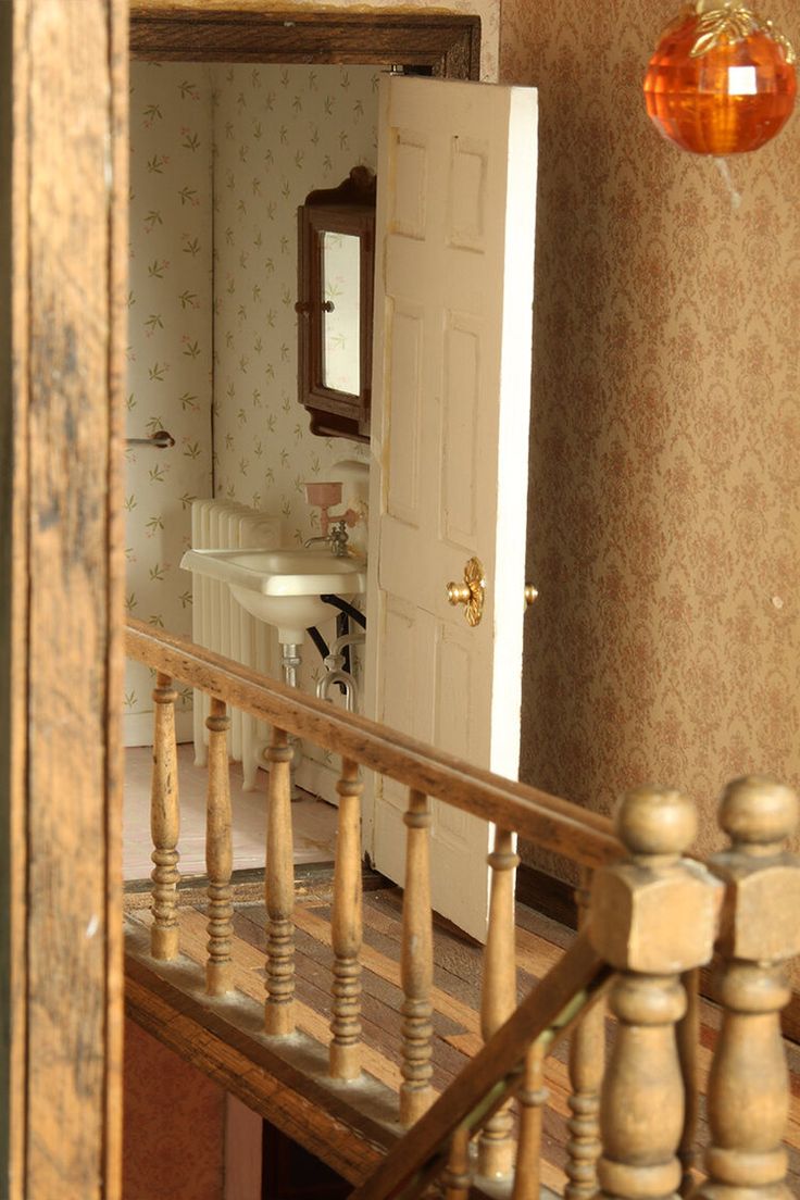 the inside of a doll house with stairs leading up to an open door that leads to a bathroom