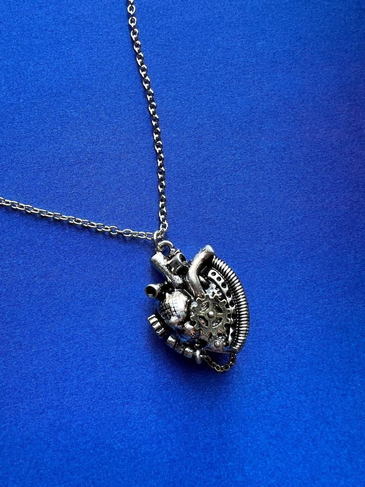 Be sentimental in style with new jewelry from Cosmic Created Magic! This steampunk heart locket necklace is a great gift for your goth girlfriend. Hanging from an 18 inch silver necklace is a steampunk heart picture locket with heart valves, gears, cogs, and knobs. Open the locket and add a photo of someone you like to keep close to your heart. You're sure to stand out with such a cool, unique locket. Punk Necklace With Lobster Clasp As Gift, Steampunk Silver Metal Necklaces, Punk Heart Necklace As A Gift, Silver Steampunk Metal Necklace, Punk Style Heart Pendant Jewelry With Heart Charm, Punk Style Nickel-free Necklace For Gifting, Punk Metal Heart Necklace For Valentine's Day, Punk Metal Jewelry For Gifts, Punk Style Metal Heart Necklace For Valentine's Day